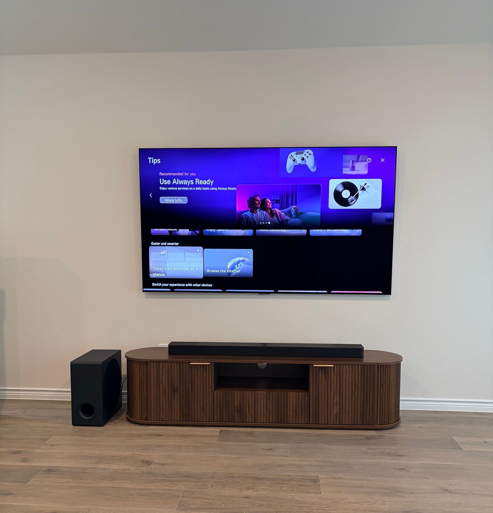 Wall-mounted LG TV with soundbar and subwoofer above a fluted walnut media console in a Dallas living room