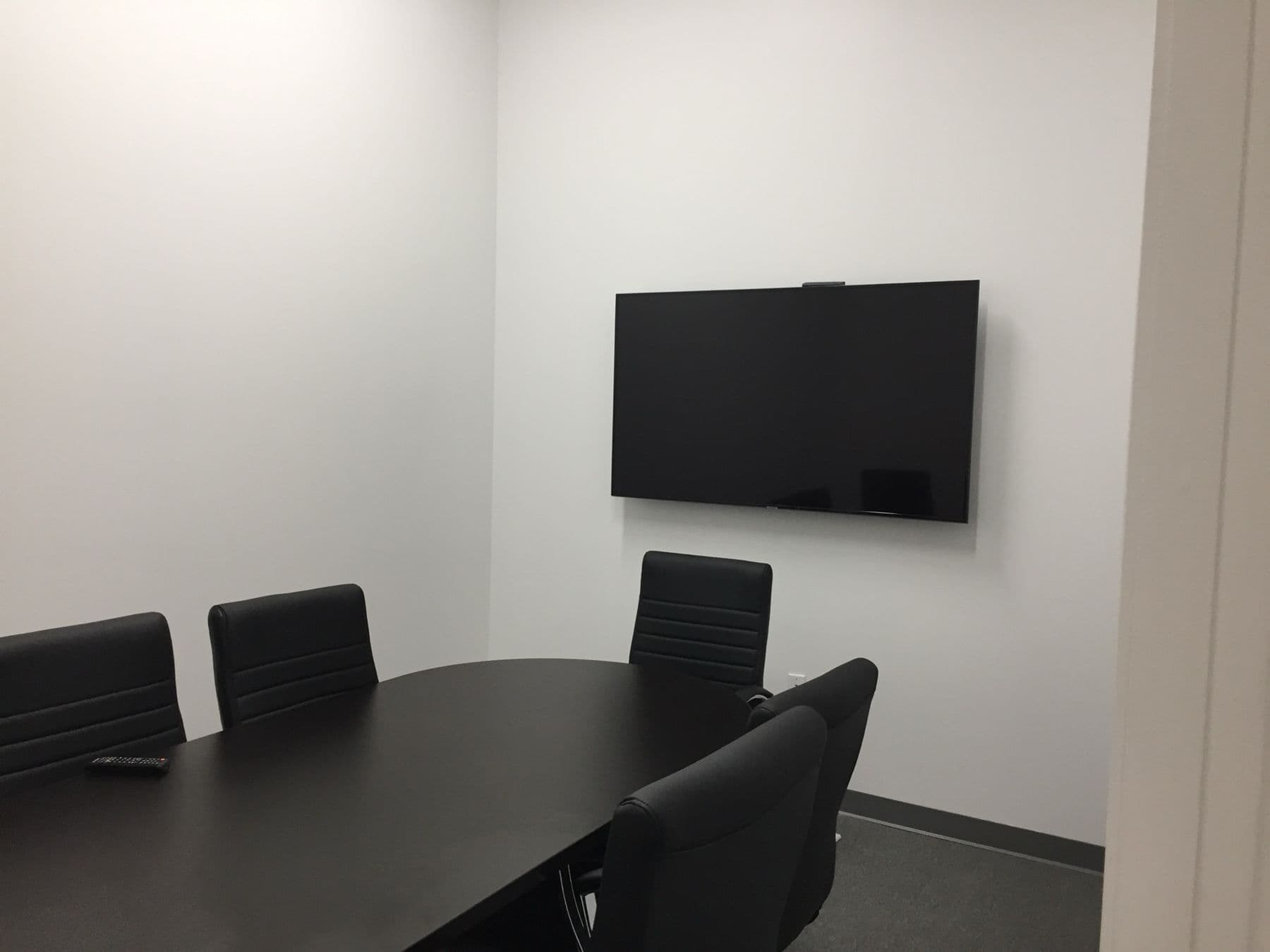 Conference room display mounted flush above the table in a Dallas office