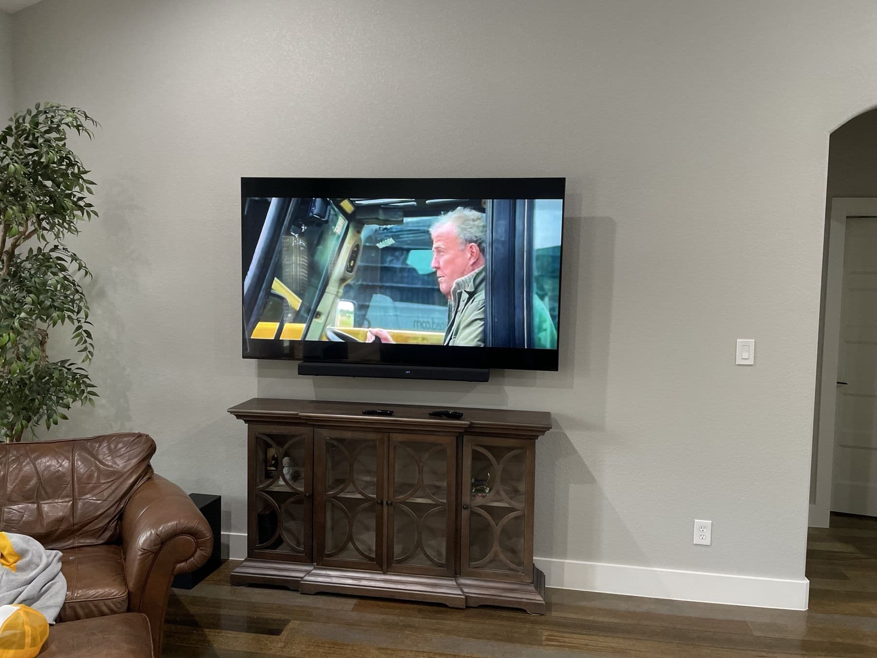 TV flush-mounted above a wood console with soundbar and in-wall cable concealment in a Dallas living room